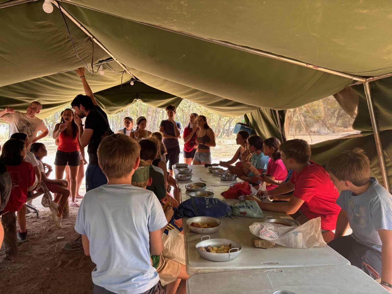 Comida en grupo bajo la carpa durante el campamento